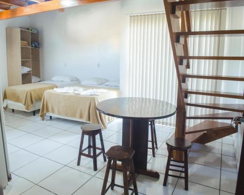 a room with a table and chairs and a bed at Pousada Bronzatto in Garopaba