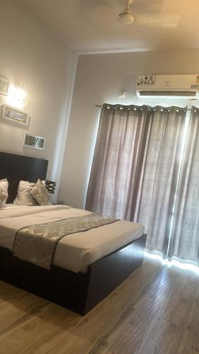 a bedroom with a bed and a window with curtains at Pearl suites at Omaxe entrenity in Vrindāvan