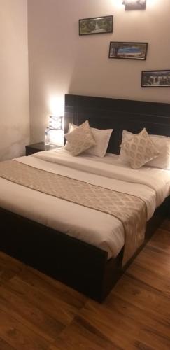 a bedroom with a large bed with white sheets and pillows at Pearl suites at Omaxe entrenity in Vrindāvan