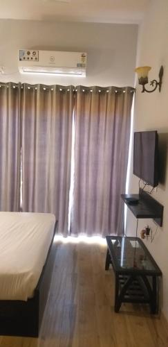 a bedroom with a bed and a television and a table at Pearl suites at Omaxe entrenity in Vrindāvan