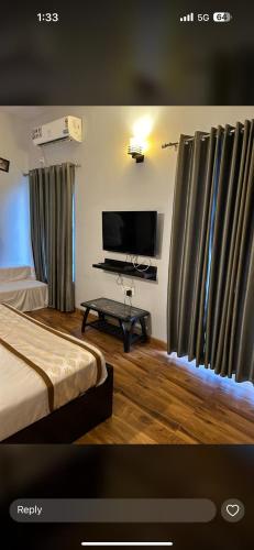 a room with a bed and a tv and curtains at Pearl suites at Omaxe entrenity in Vrindāvan