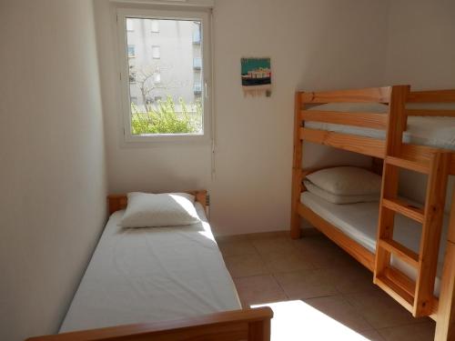 une chambre avec deux lits superposés et une fenêtre dans l'établissement Gruissan : T3 Pieds dans l'eau, Piscine, Parking, 6/7 pers, Confort Moderne - FR-1-796-64, à Gruissan