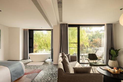 a living room with a large tub and a bedroom at 乌镇乌外坞酒店 in Tongxiang
