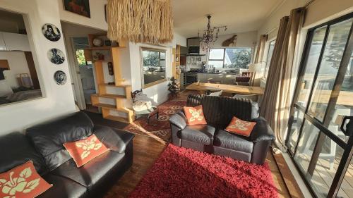 a living room with two leather couches and a table at Beachfront Sunset Bach in Piha