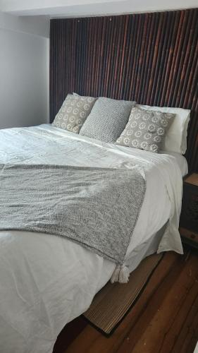 a bedroom with a bed with white sheets and pillows at Beachfront Sunset Bach in Piha