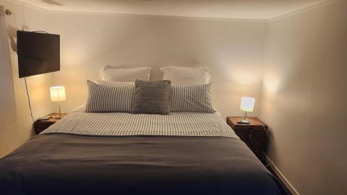 a bedroom with a large bed with two lamps at Beachfront Sunset Bach in Piha
