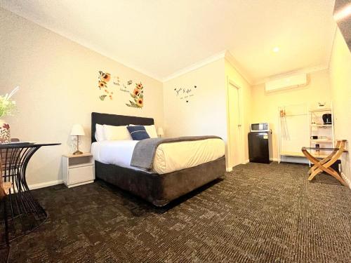 a bedroom with a bed and a table and a refrigerator at Seven Inn in Wagga Wagga