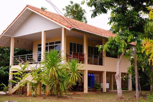 a house withtropical plants in front of it at Baan Ob-oun Homestay in Ban Khlong Chi Lat