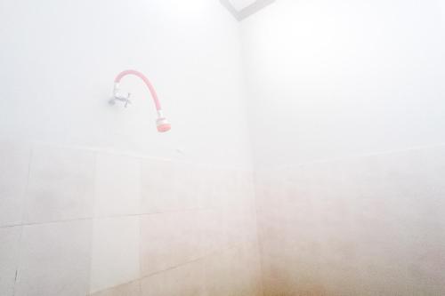 a shower with a shower head in a bathroom at Astri Homestay Carkranegara Mataram Mitra RedDoorz in Tjakranegara