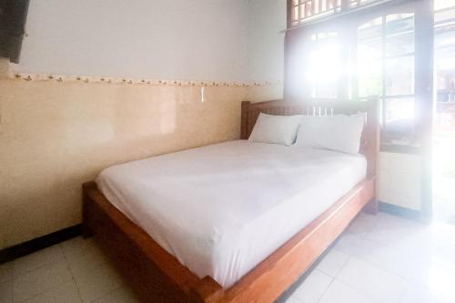 a bedroom with a bed with white sheets and a window at Astri Homestay Carkranegara Mataram Mitra RedDoorz in Tjakranegara