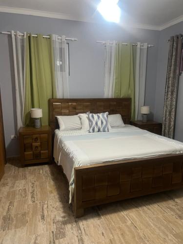 a bedroom with a large bed with white sheets and green curtains at Laguna beach in Sosúa