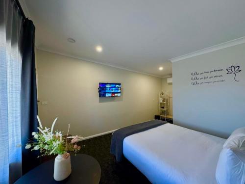 a bedroom with a bed and a tv on the wall at Seven Inn in Wagga Wagga