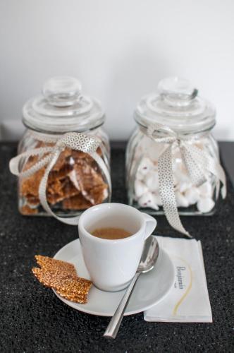 a cup of coffee on a plate next to glass jars at Benjamin Business Hotel in Herzelia 