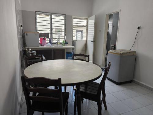 a kitchen with a table and chairs in a room at Putera Indah Homestay Batu Pahat 13 pax by Ngio in Batu Pahat
