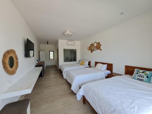 a hotel room with three beds and a television at Myhoa Lagoon - Kiting Town in Phan Rang