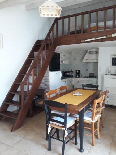 une cuisine avec une table et des chaises ainsi qu'un escalier dans l'établissement Les volets bleus, à Saint-Gilles-Croix-de-Vie