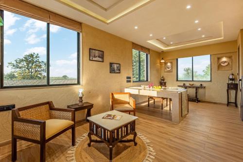 a living room with a table and chairs and windows at Sterling Orient Woods Pench in Silāri