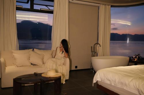 a woman sitting on a couch in a hotel room at Erhai Seaview Garden Villa &Dali Airport in Dali
