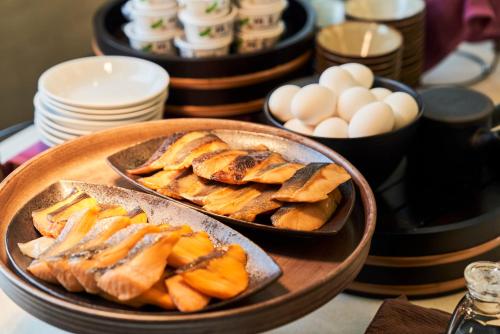 a table with plates and bowls of bread and eggs at Hotel Global View Hachinohe Annex in Hachinohe