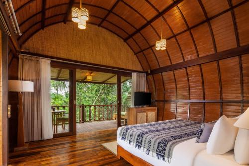 a bedroom with a bed and a balcony at Beehouse Dijiwa Ubud in Ubud