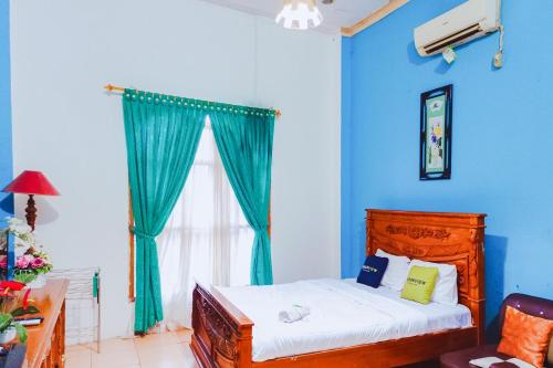 a bedroom with a bed with blue walls and a window at Urbanview at Wedika Hotel Bengkulu in Bengkulu