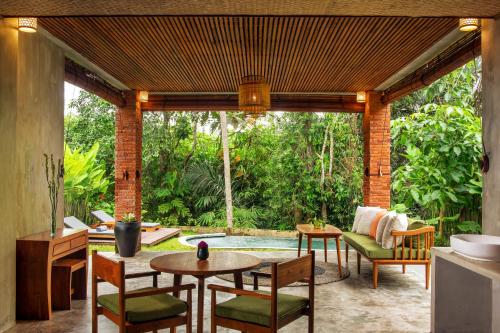 a patio with a table and chairs and a pool at Beehouse Dijiwa Ubud in Ubud