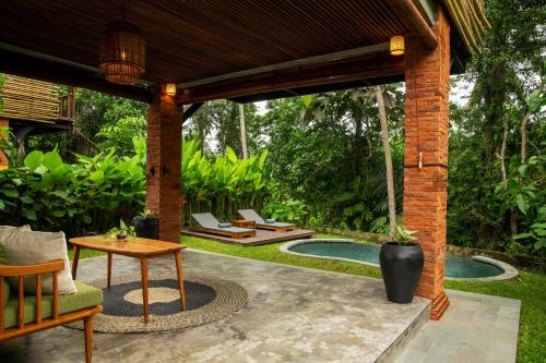 a pavilion with a table and chairs and a pool at Beehouse Dijiwa Ubud in Ubud