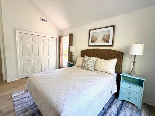 a bedroom with a white bed with a blue nightstand and a door at 2975 Deer Point Dr in Johns Island