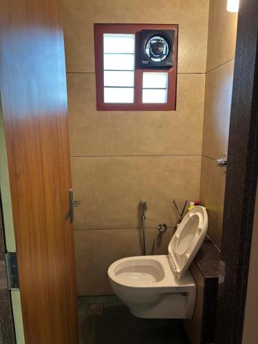 a bathroom with a toilet and a window at Coastal Stay with private Beach Access KAPU in Udiyāvara