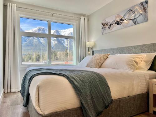 a bedroom with a large bed with a large window at Mountain View New Luxury Condo at Banff Entrance in Canmore
