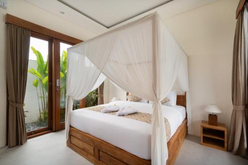 a bedroom with a bed with a canopy at Oemah Manureva Ubud in Mambat