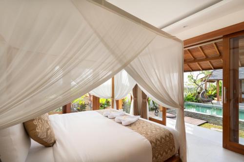 a bedroom with a white bed with a canopy at Oemah Manureva Ubud in Mambat