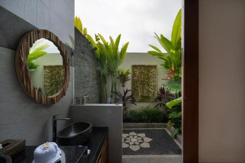 a bathroom with a sink and a mirror and plants at Oemah Manureva Ubud in Mambat