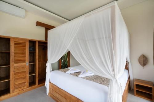 a bedroom with a canopy bed with white curtains at Oemah Manureva Ubud in Mambat