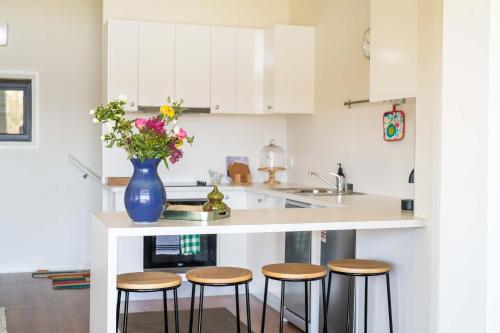 una cocina con encimera con taburetes y un jarrón con flores en Mortimer's Wines Loft - Adults Only Retreat, en Orange