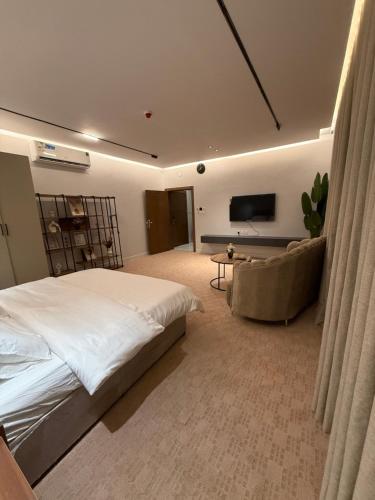 a bedroom with a bed and a couch and a television at افاق المسكن in Al Madinah