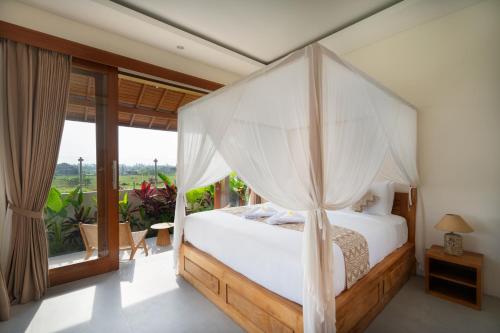 a bedroom with a bed with a canopy at Oemah Manureva Ubud in Mambat