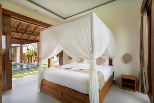 a bedroom with a bed with a canopy at Oemah Manureva Ubud in Mambat