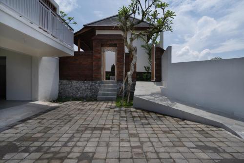 a house with a white wall and a brick driveway at Oemah Manureva Ubud in Mambat