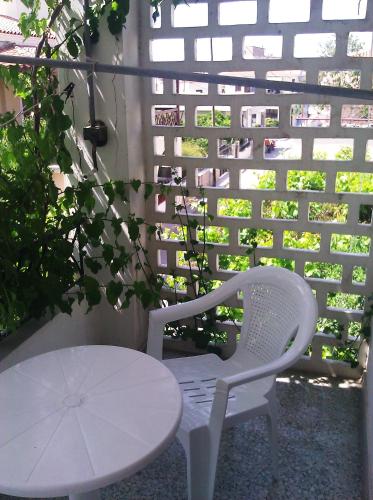 a white table and a white chair and a table and umbrella at Captain's Rooms in Aegina Town