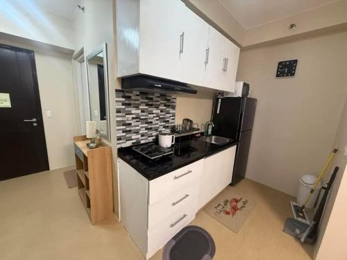 a kitchen with white cabinets and a black counter top at Amoore Avida Tower 2 in Cagayan de Oro