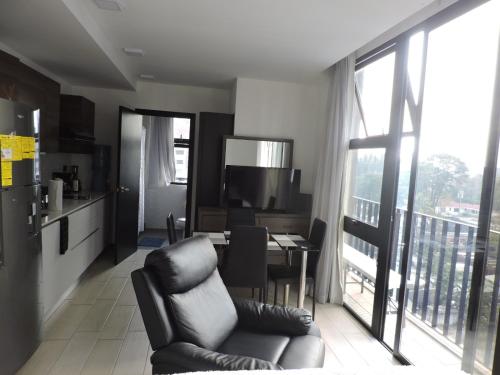 a living room with a chair and a kitchen with a table at Loft urbano, Ciudad Guatemala, EON in Estación Pamplona