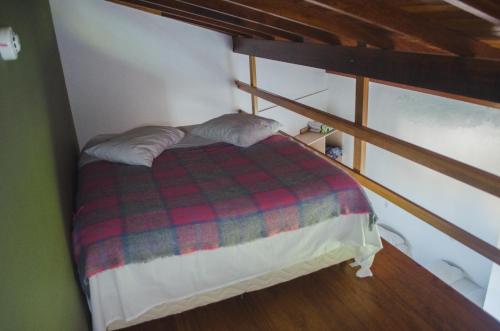 a bed with a plaid blanket in a room at Pousada Bronzatto in Garopaba