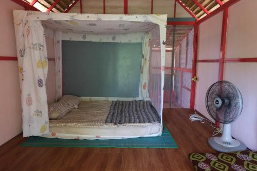 a bed in a tent in a room with a fan at Presente in Ko Phayam