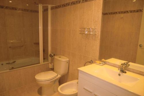 a bathroom with a toilet and a tub and a sink at Hotel Vila Mar in Cambrils