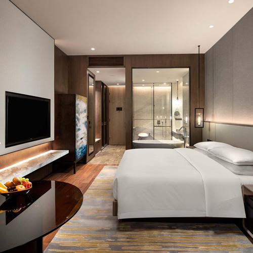 a bedroom with a large white bed and a television at New Century Mansion Hotel Changzhou in Changzhou