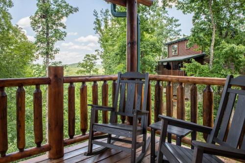 two chairs on a deck with a cabin in the background at The Bear Club in Pigeon Forge