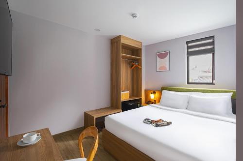 a bedroom with a large white bed and a table at Nature Hotel - Win Happy in Da Lat
