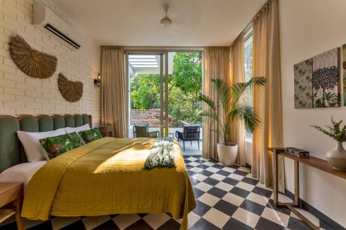 a bedroom with a yellow bed and a checkered floor at La Masillia, 2 BHK with Private Pool, 15 mins from Morjim Beach, Wifi, Peaceful location, Kitchen, Security, Patio in Siolim