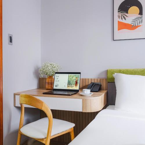 a desk with a laptop and a chair next to a bed at Nature Hotel - Win Happy in Da Lat